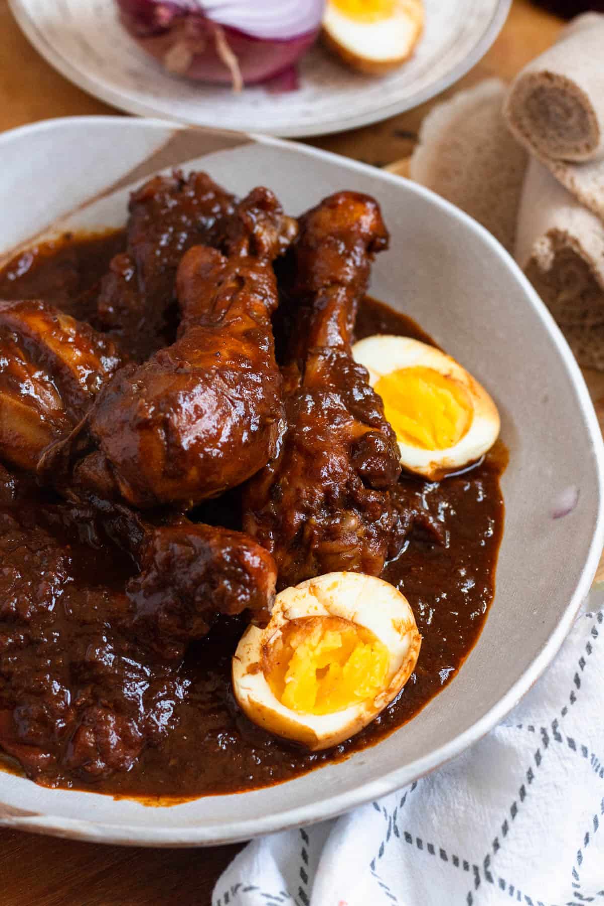 A bowl of Ethiopian Doro Wat with boiled eggs in a rich, spiced sauce.