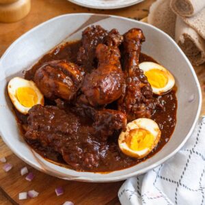 A bowl of Ethiopian Doro Wat with chicken drumsticks and boiled eggs in a rich, spiced sauce.