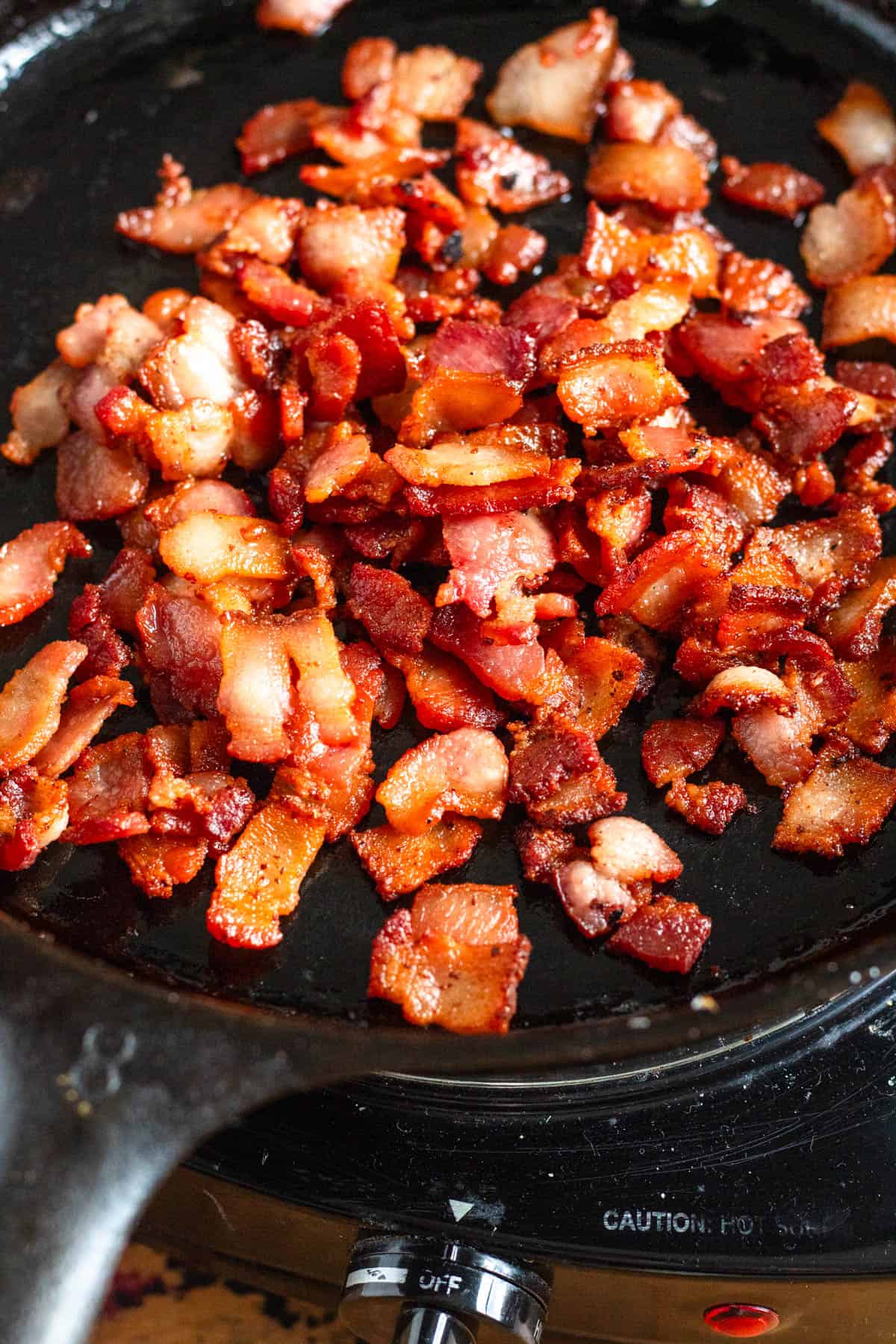 Crispy bacon pieces frying in a hot pan.