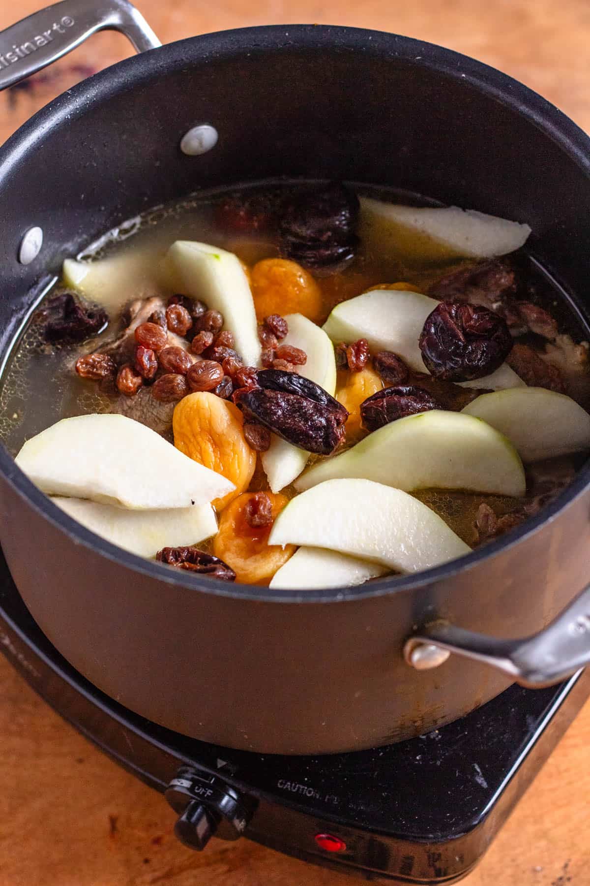 Lamb simmers with cinnamon, water, and sugar before dried fruits and pears are added.