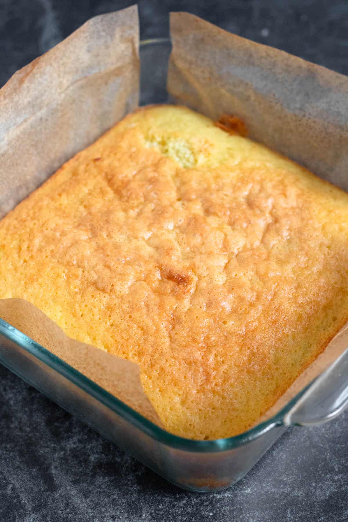 A freshly baked cake resting in a pan to cool.