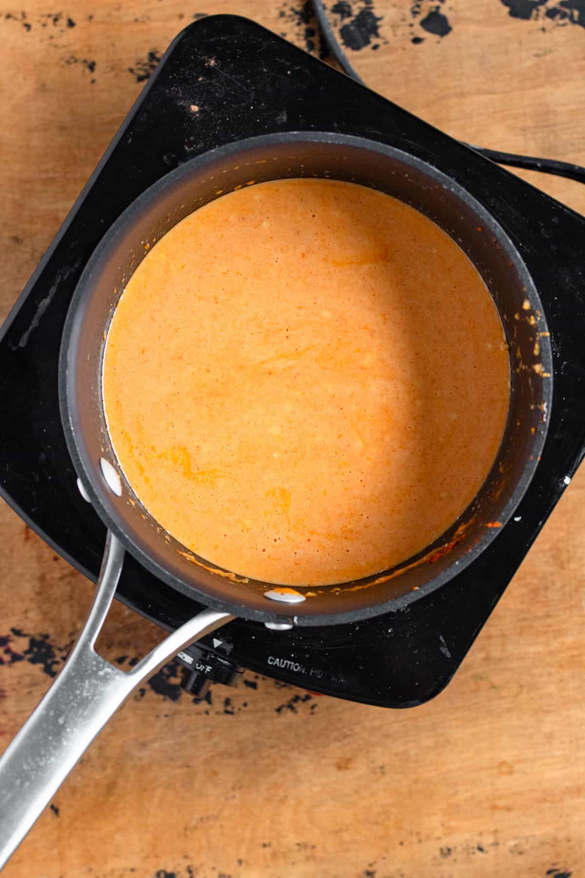 Coconut milk gently simmers with curry paste in the pot.