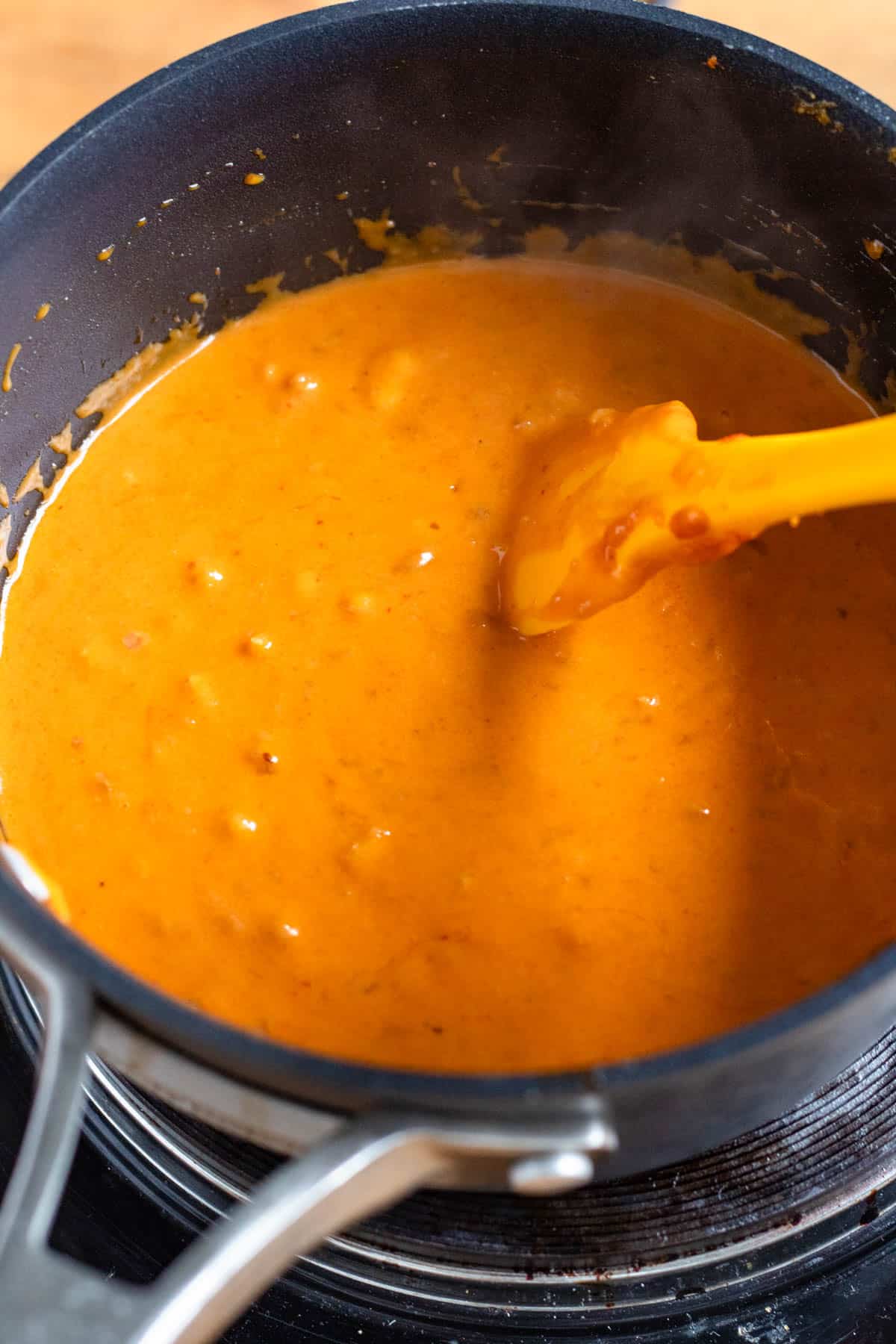 Thai peanut sauce simmers in the pot, thick and creamy.
