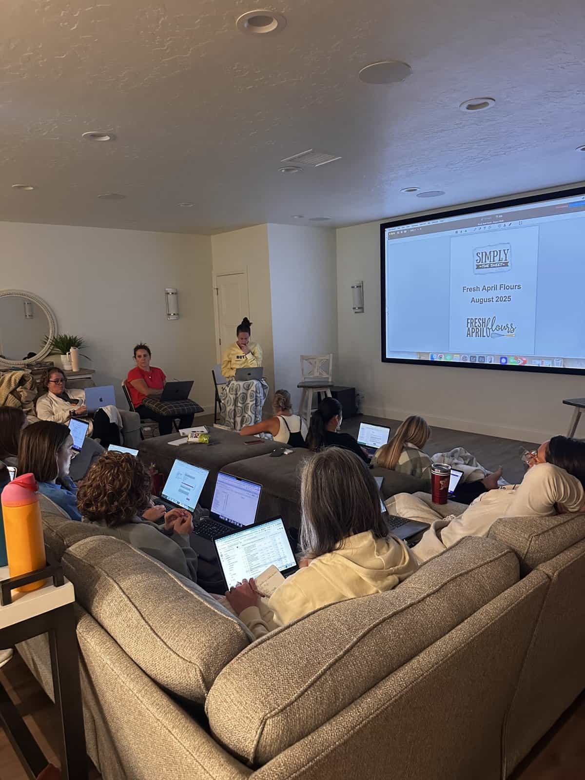 A room of bloggers on their computers learning from each other with a big screen in front