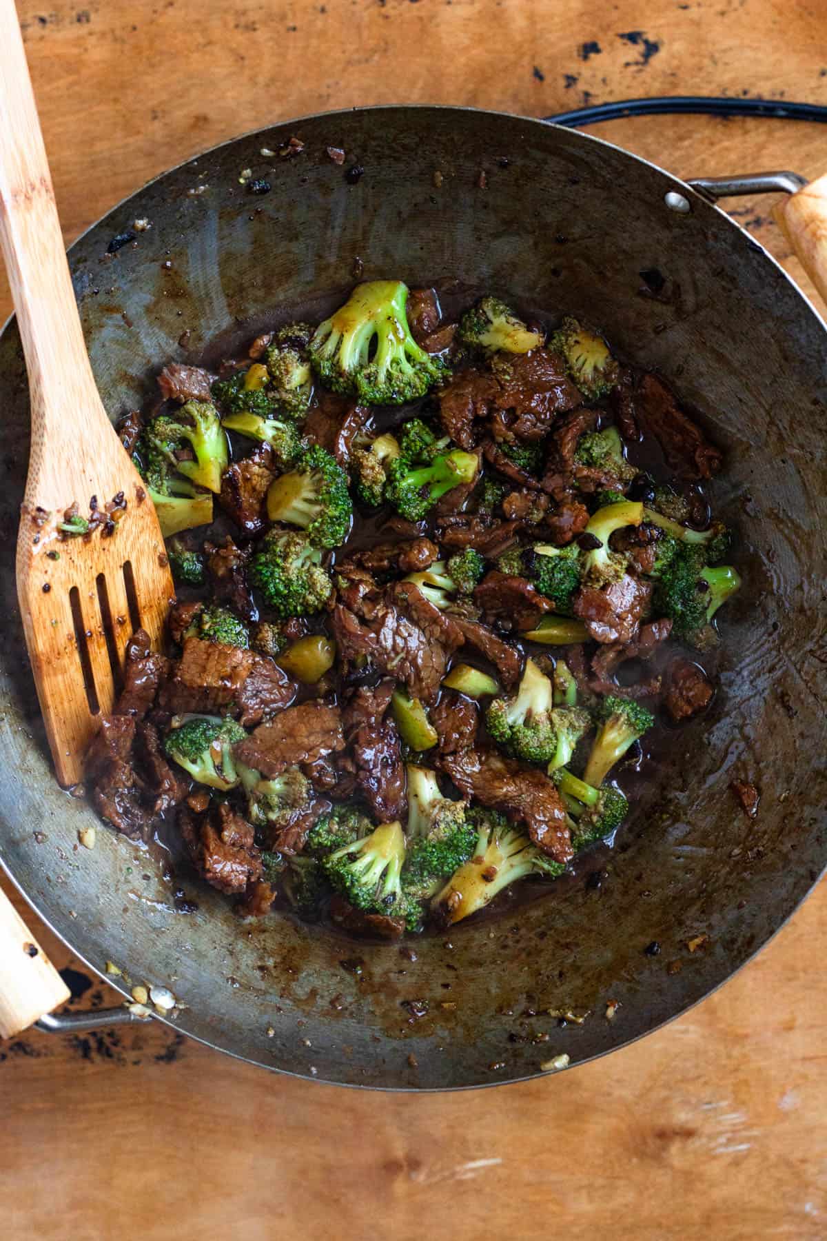 Sauce poured into the wok, coating the beef and broccoli as it simmers and thickens.