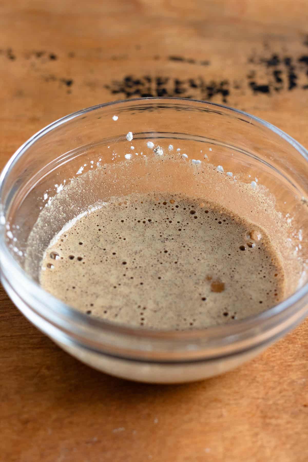A bowl containing a mixed marinade of baking soda, soy sauce, Chinese cooking wine, water, cornstarch, and white pepper.
