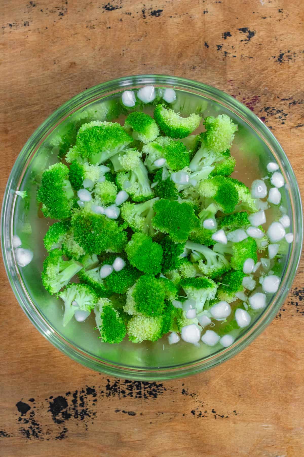 Cooked broccoli placed in a bowl of ice water to stop the cooking process.