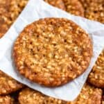 Crispy benne seed cookies stacked on parchment paper.