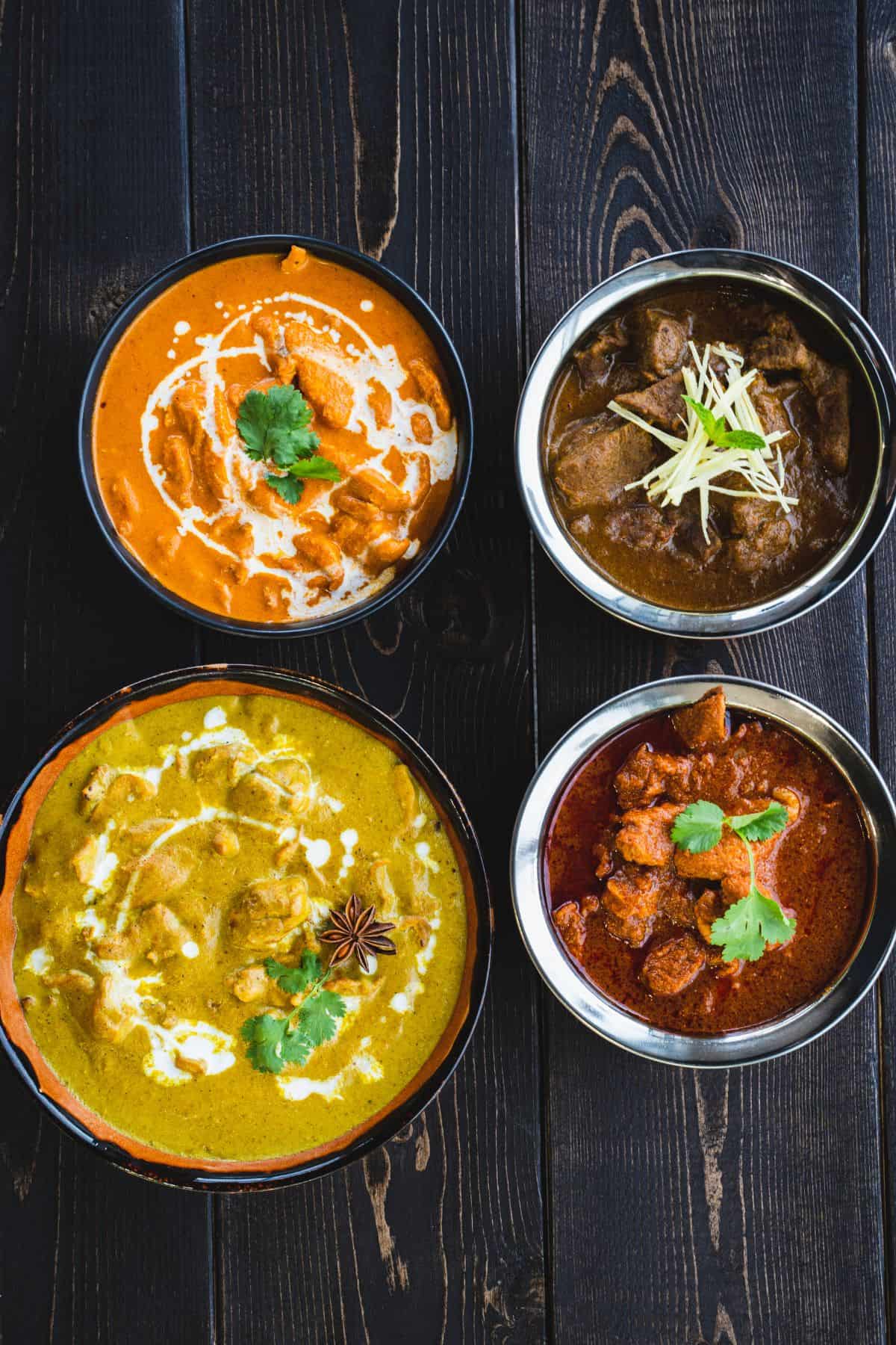 Butter chicken and tikka masala bowls on a dark wooden table.