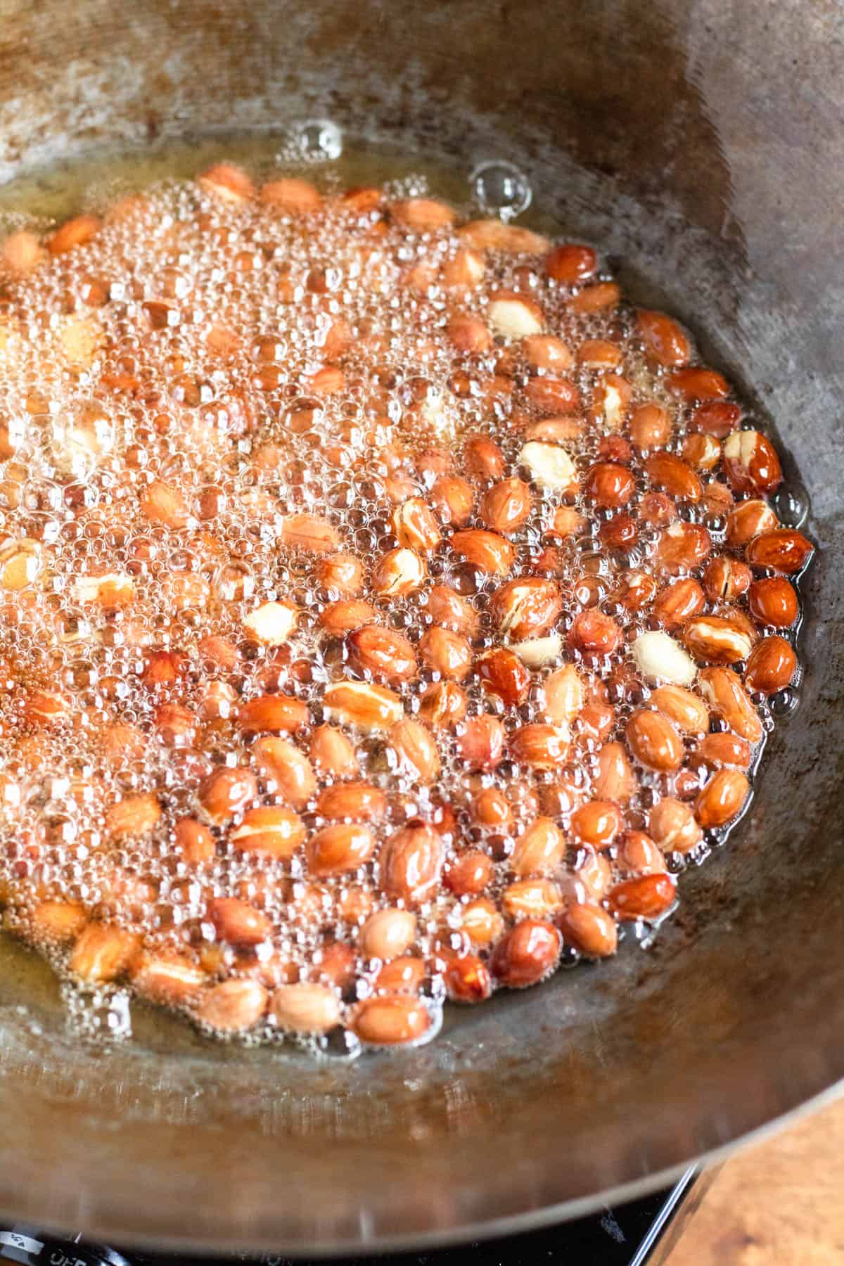 Peanuts frying in a pan of hot oil.