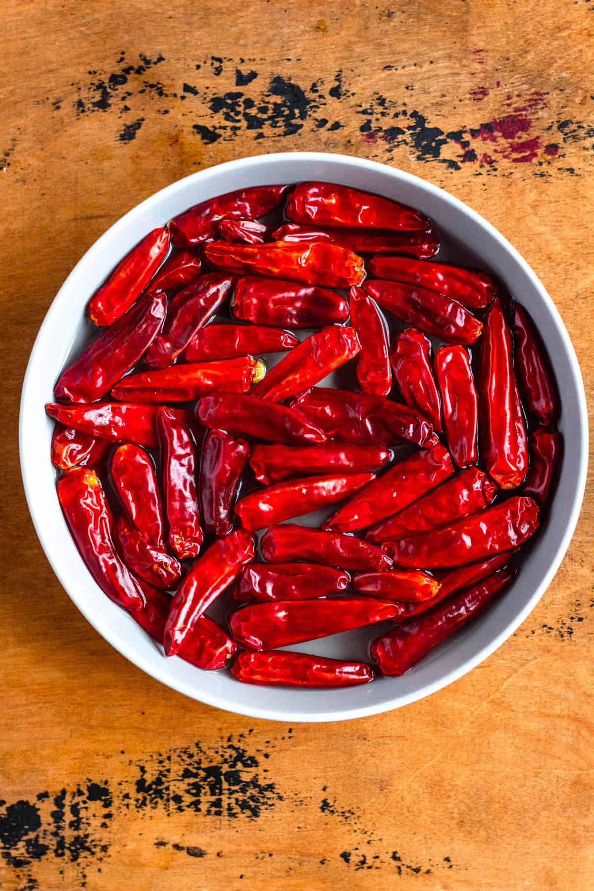 Red chili peppers soaking in a bowl of boiling water.