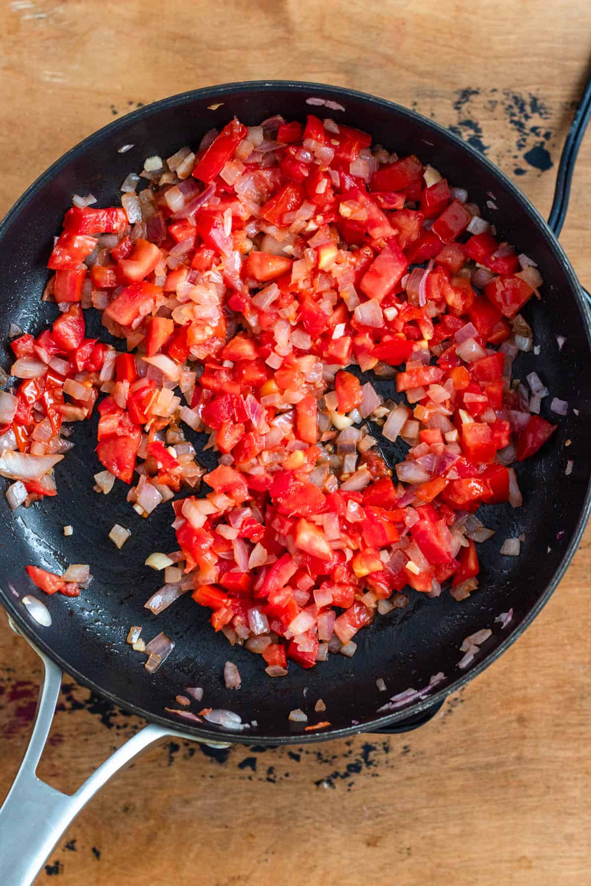 Onions, garlic, and tomatoes sautéed in a pan.