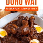 Pinterest image of a bowl of Ethiopian Doro Wat with boiled eggs in a rich, spiced sauce.