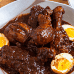 Pinterest image of a bowl of Ethiopian Doro Wat with boiled eggs in a rich, spiced sauce.