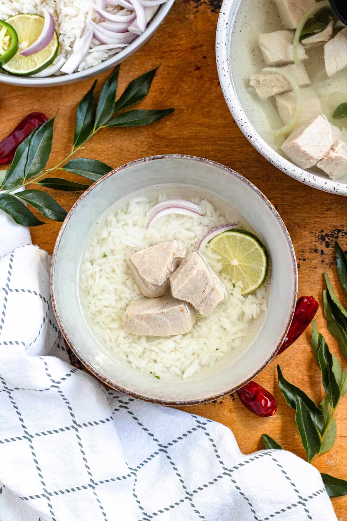 Top image of a bowl of Garudhiya, a Maldivian fish soup served with rice, red onions, and lime.
