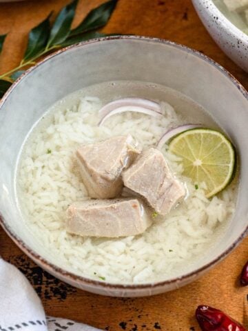 A bowl of Garudhiya, a Maldivian fish soup served with rice, red onions, and lime.