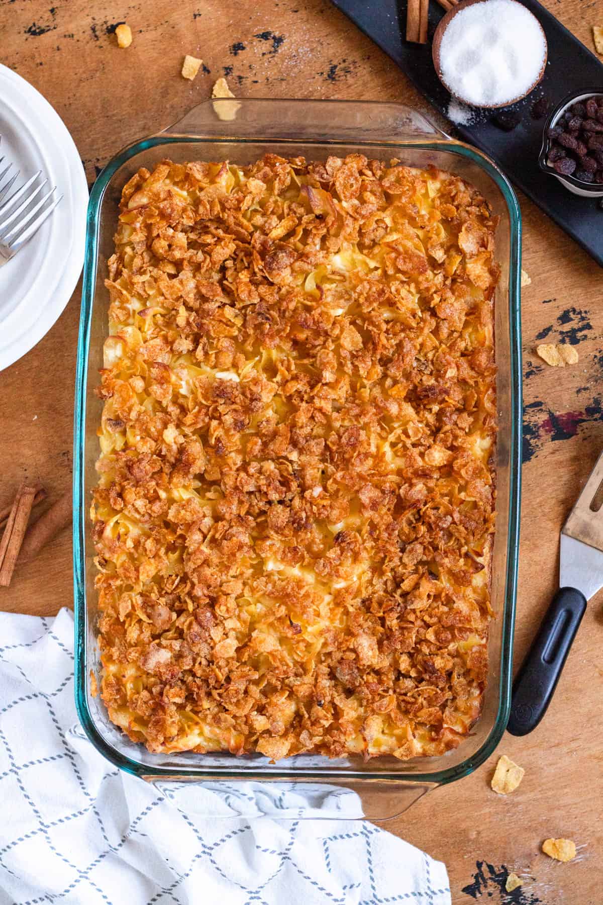Cornflake topping being added over the noodle mixture before baking.
