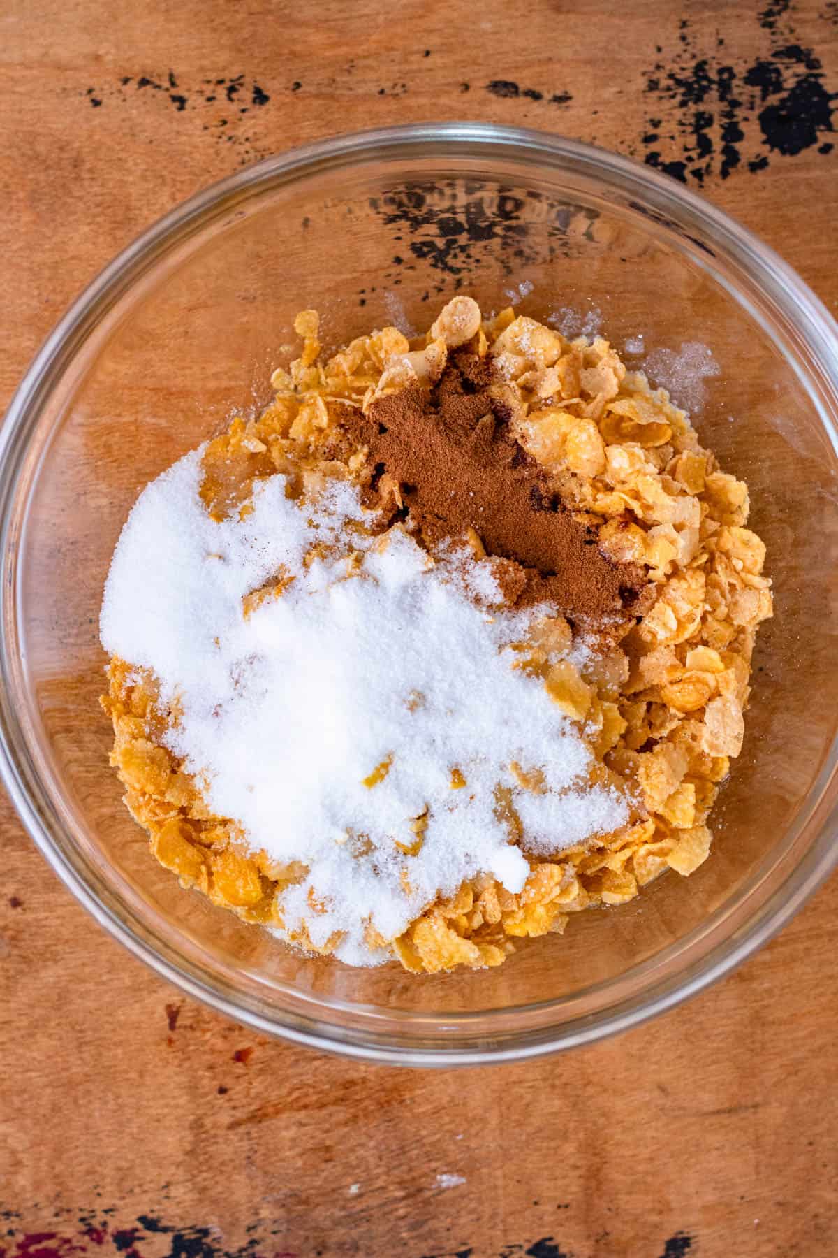 Cornflakes, butter, sugar, and cinnamon mixed together in a bowl to create the topping.