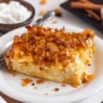 A close-up of a baked noodle kugel slice topped with a crunchy golden cornflake crust on a white plate.