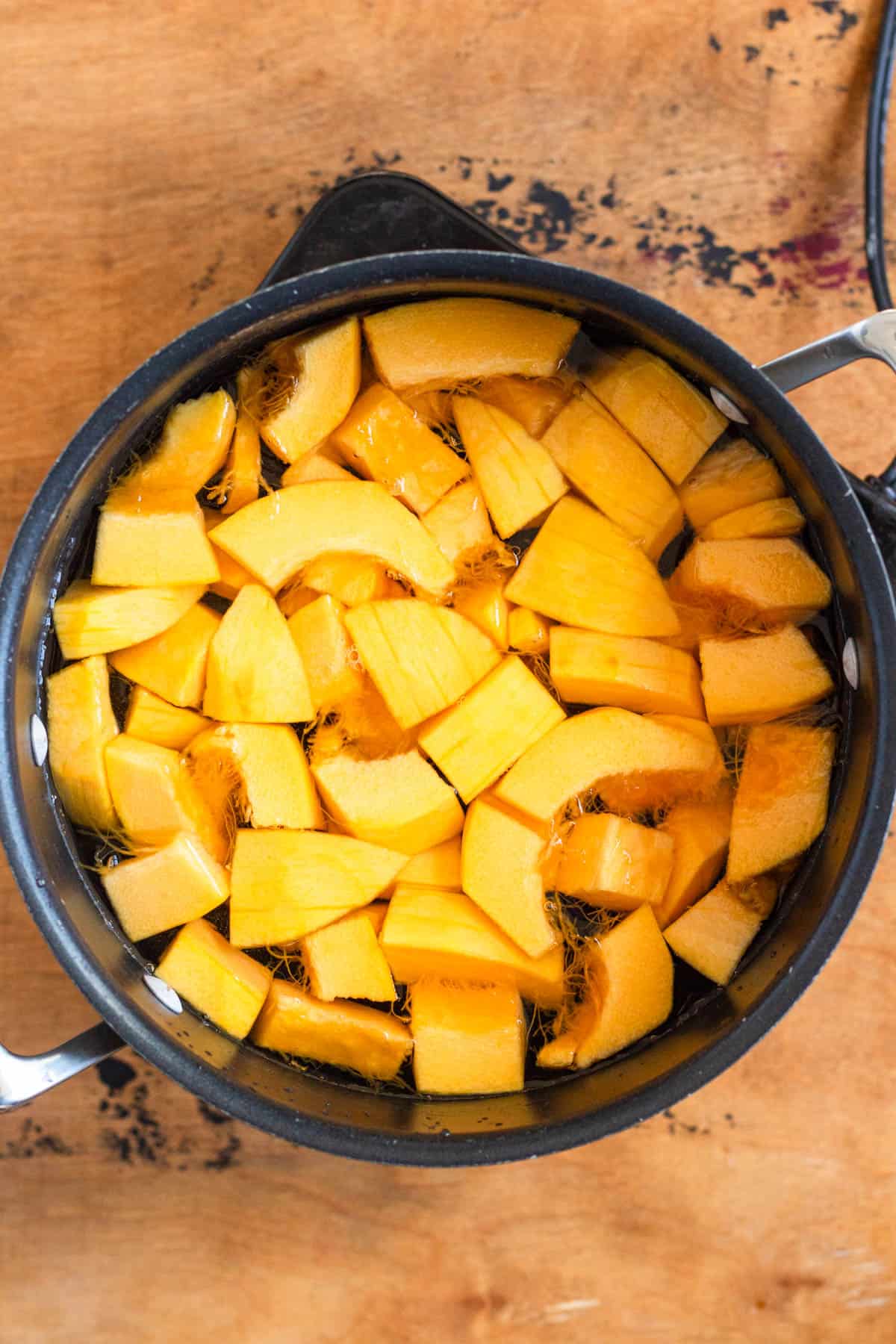 Pumpkin pieces submerged in a pot of water, ready to boil.
