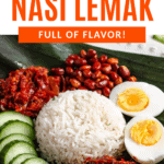 Pinterest image of a close-up view of a plate of Malaysian Nasi Lemak served with rice, sambal, boiled egg, peanuts, anchovies, and cucumber slices on a banana leaf.