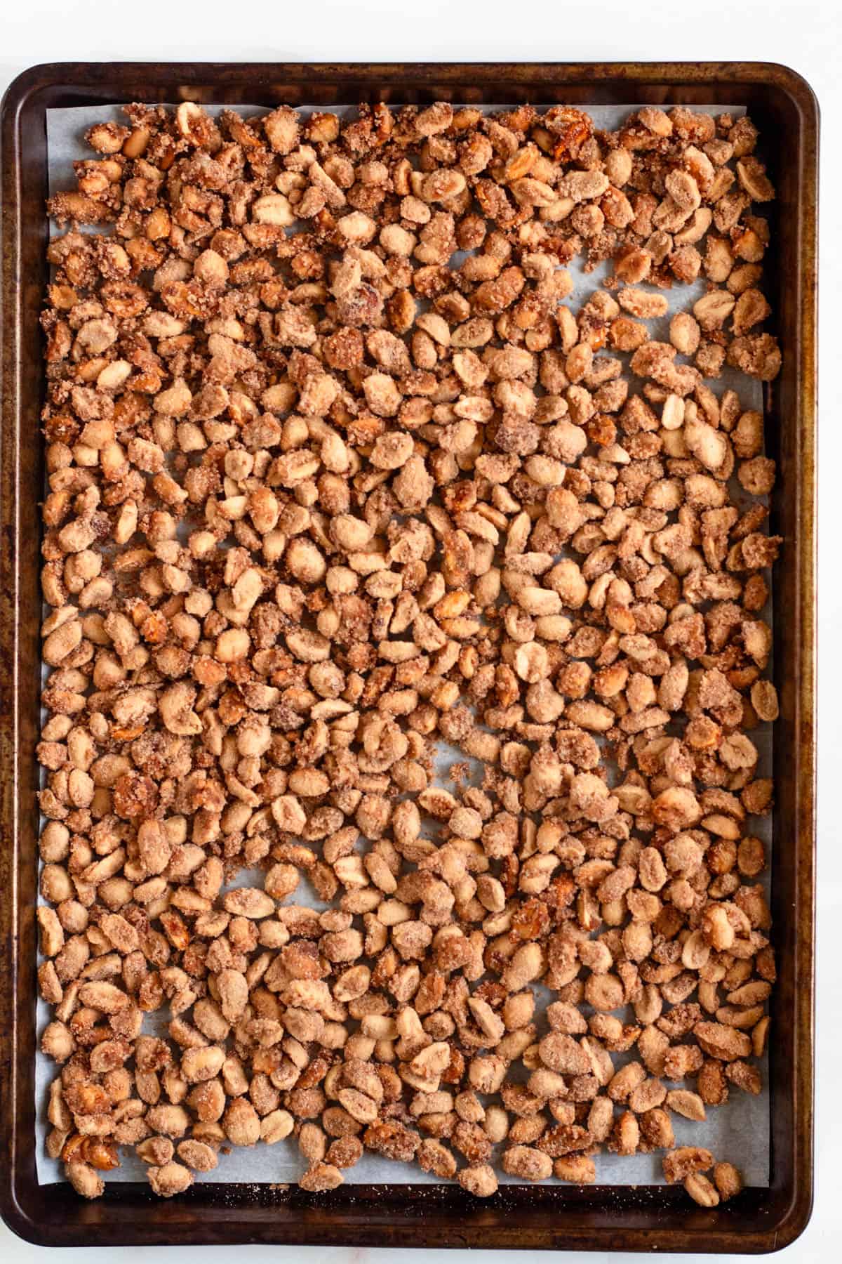 Candied peanuts on a parchment-lined baking sheet.