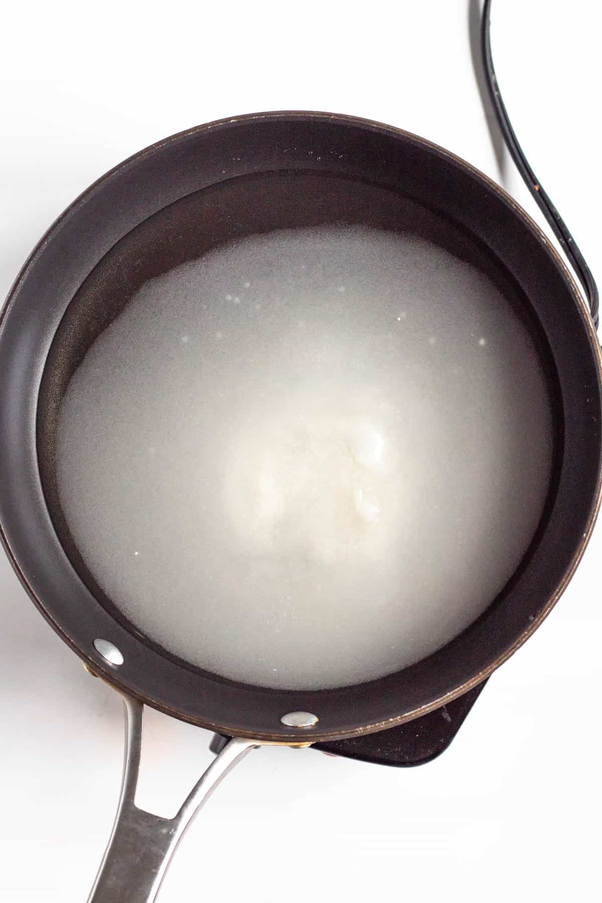 Sugar and water simmer in a saucepan.