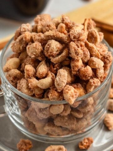 Candied peanuts coated in a crunchy sugar crust in a glass cup.