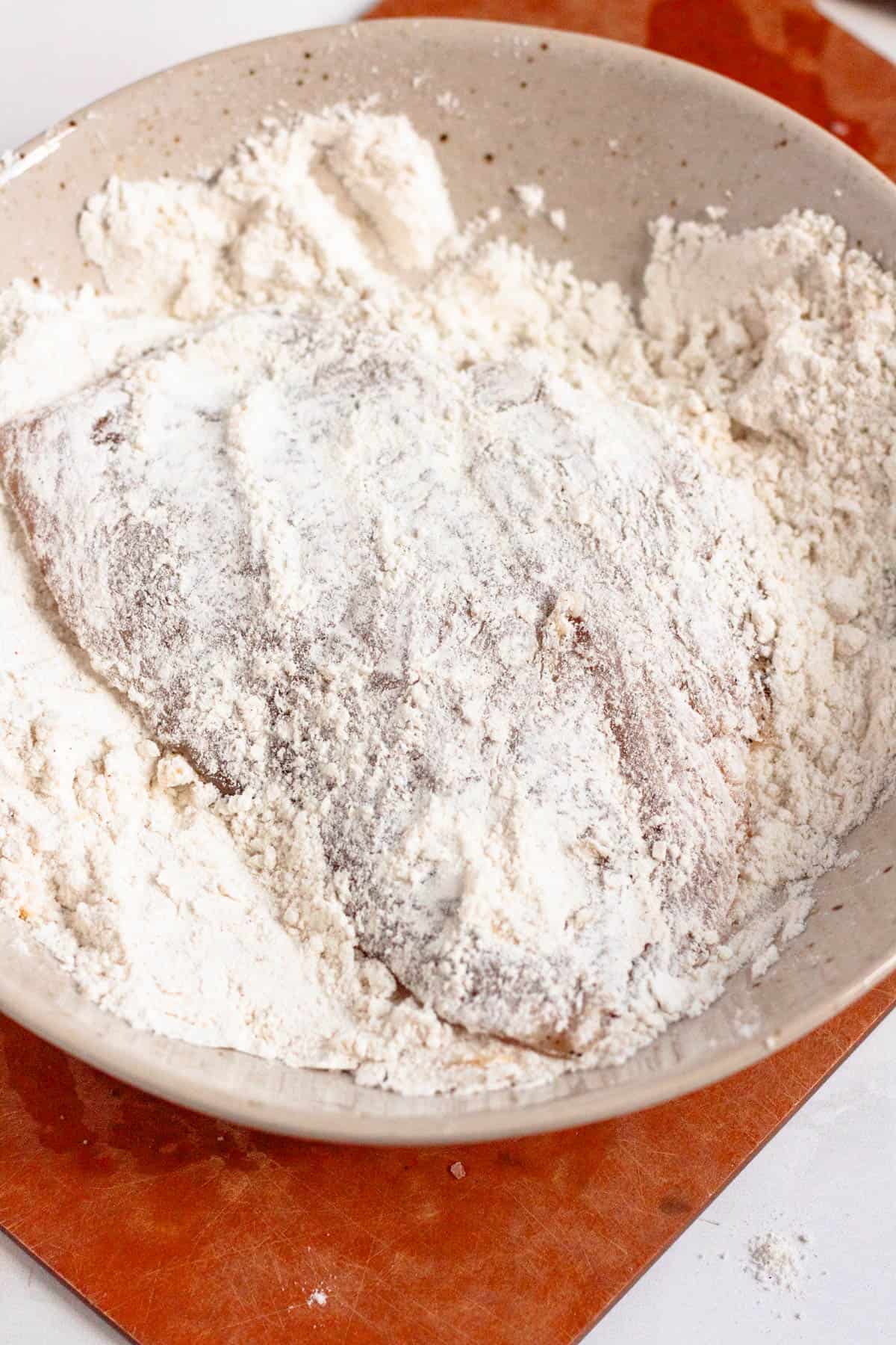 Chicken cutlets coated evenly in flour on both sides.