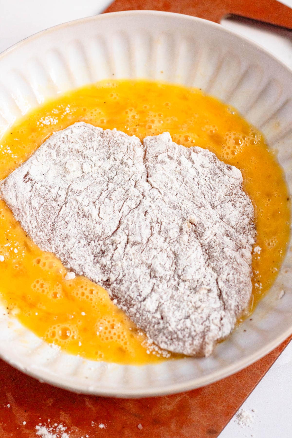 Chicken cutlets coated in beaten egg on both sides.