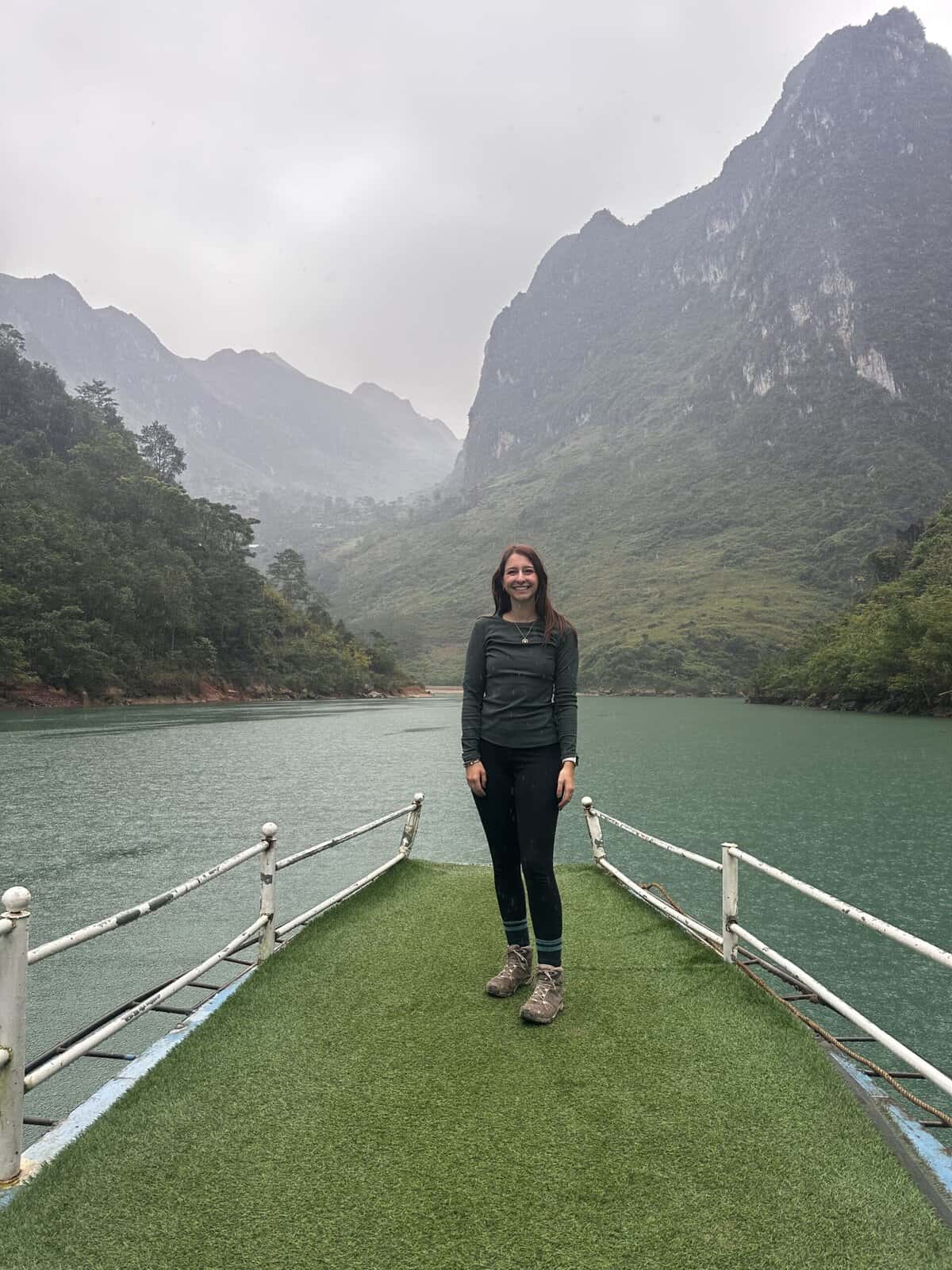 A girl standing on a boat in front of a canyon.
