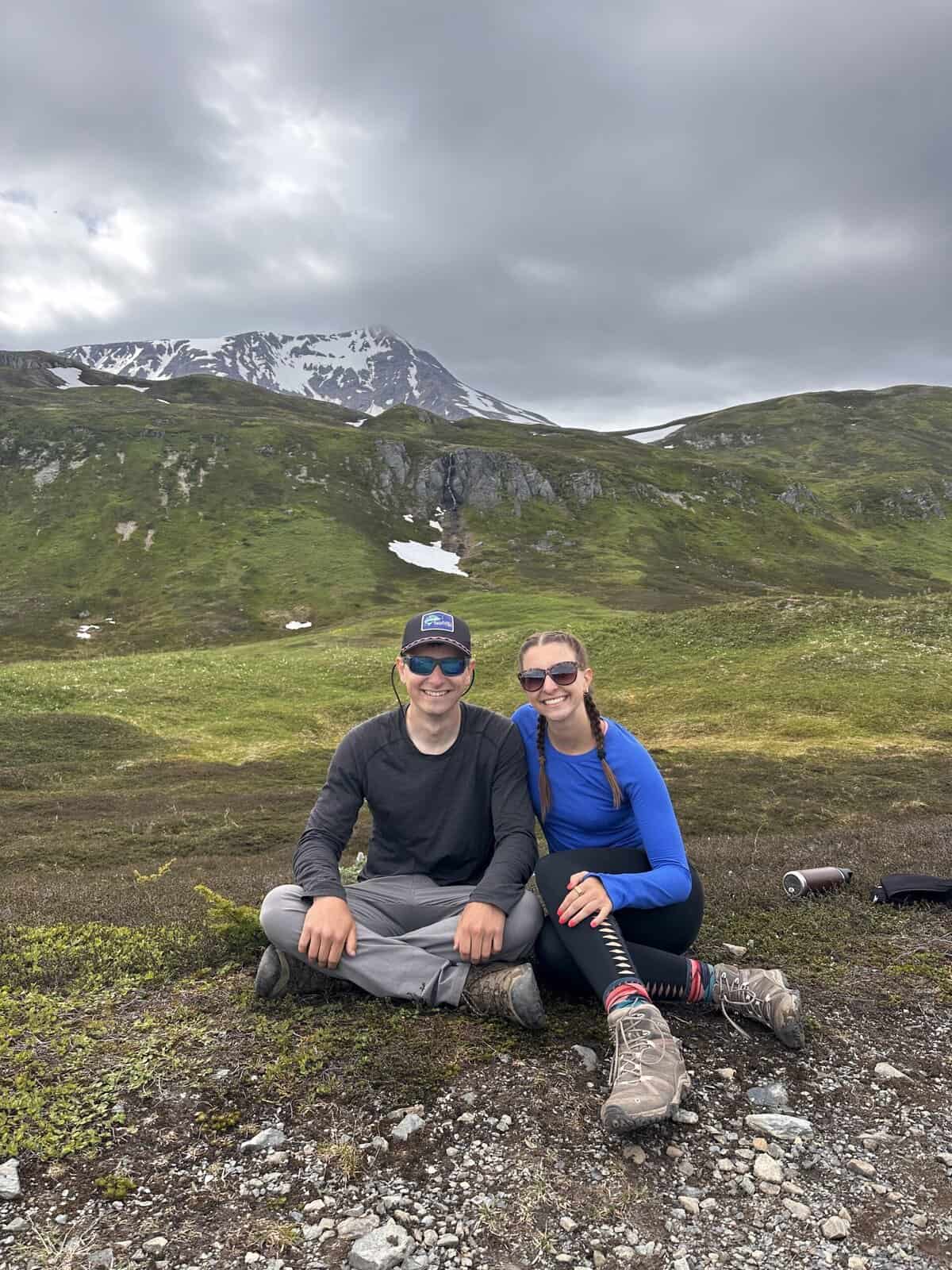 Adult siblings smiling in front of an Alaska mountain