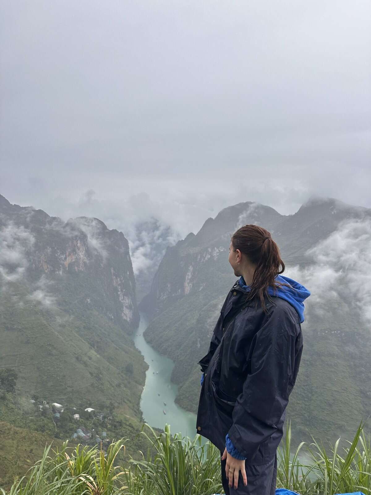 A girl standing in front of a canyon with a river running through it.
