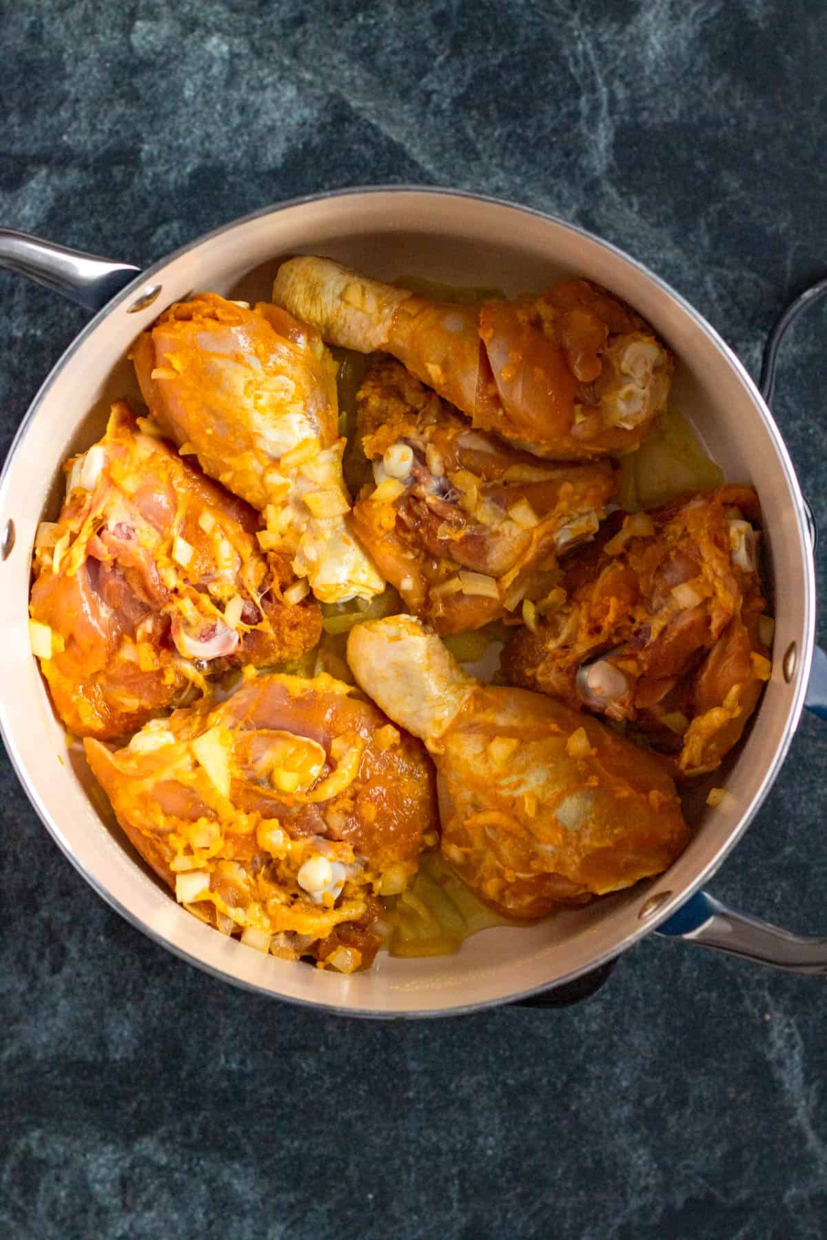 Chicken pieces browning in a large pot with oil.