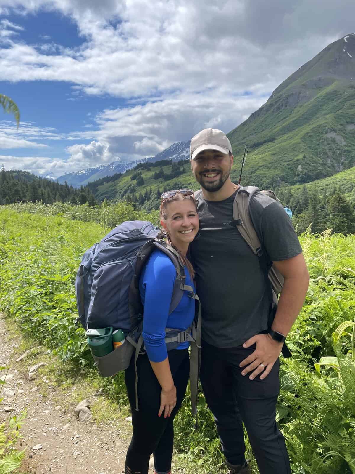 a man and woman smiling with backpacks on 