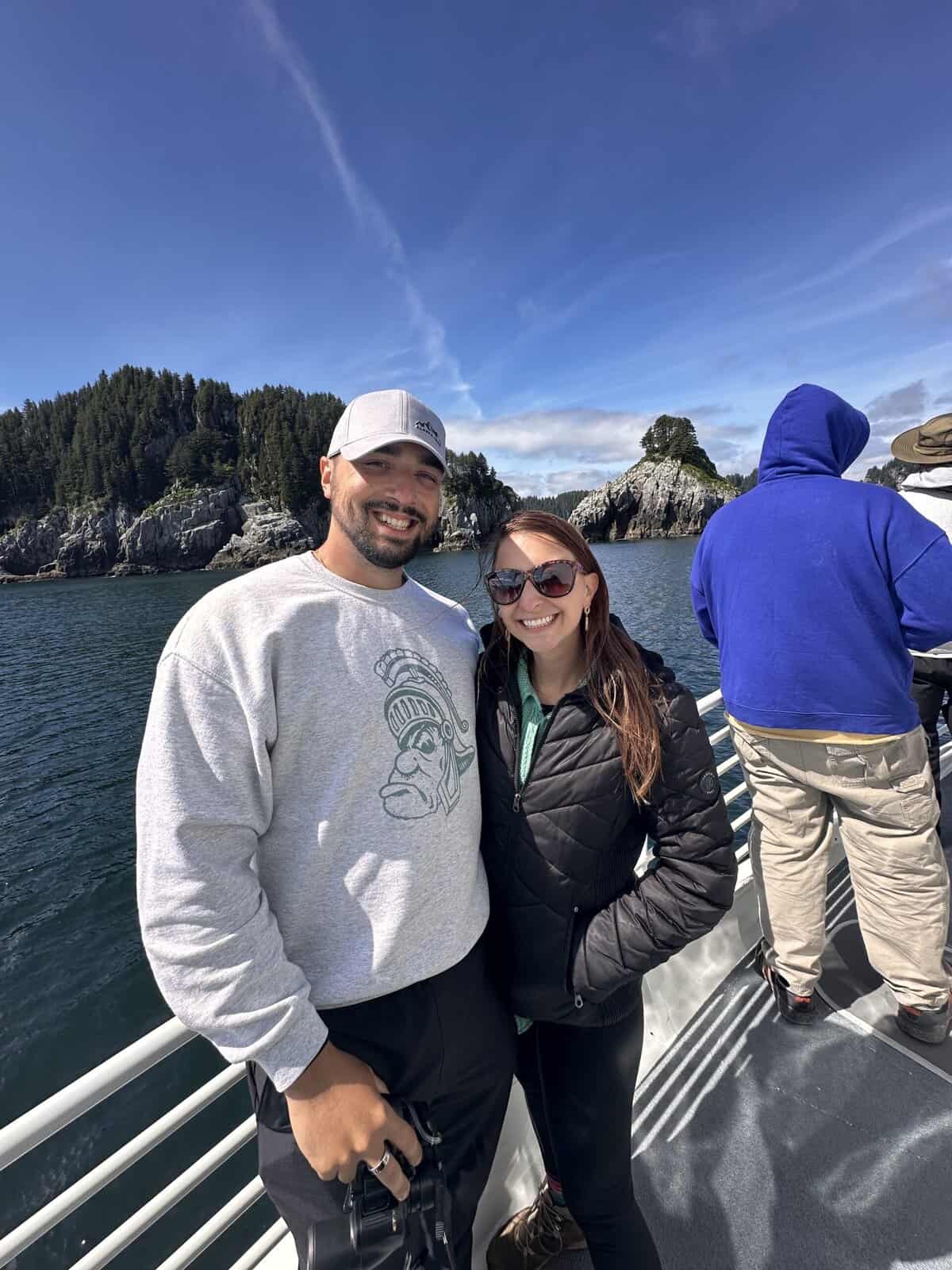 A couple posing on a boat in kenai fjords national park