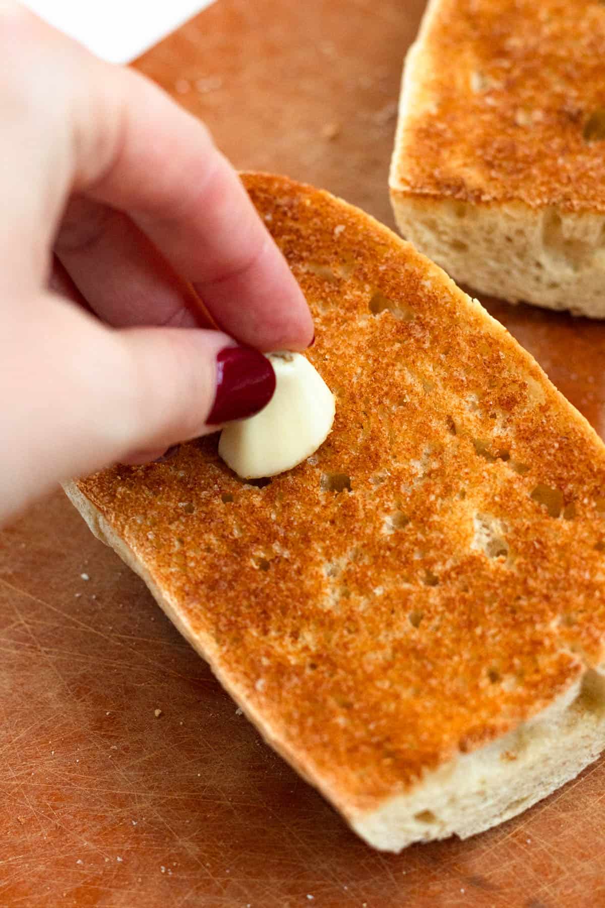 Rubbing fresh garlic onto both sides of the toasted bread.