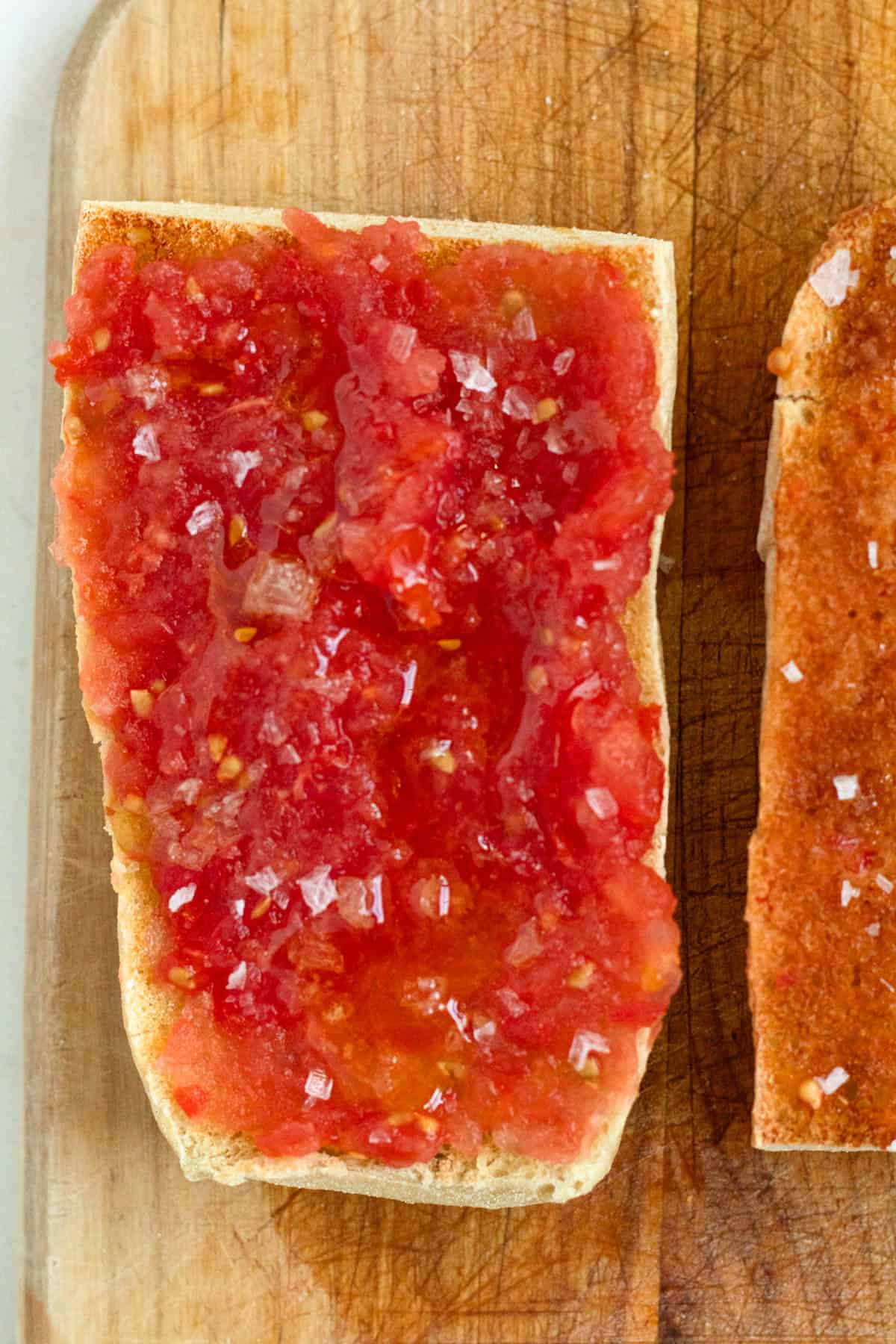 Fresh tomatoes grated on a large cheese grater, with the juicy pulp spooned generously over each slice of bread.
