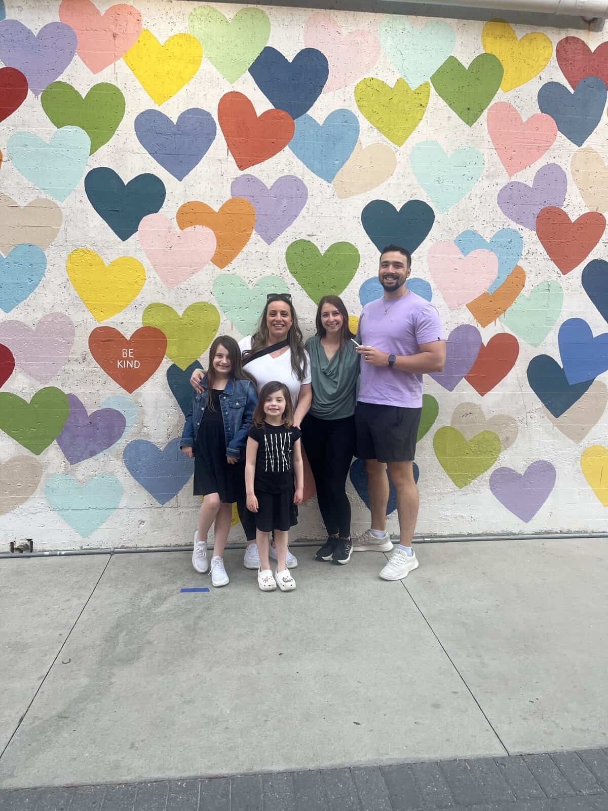 a family posing in front of a heart mural