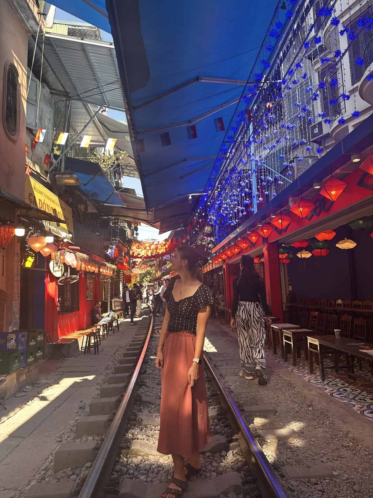 A girl standing in train street with a skirt on.