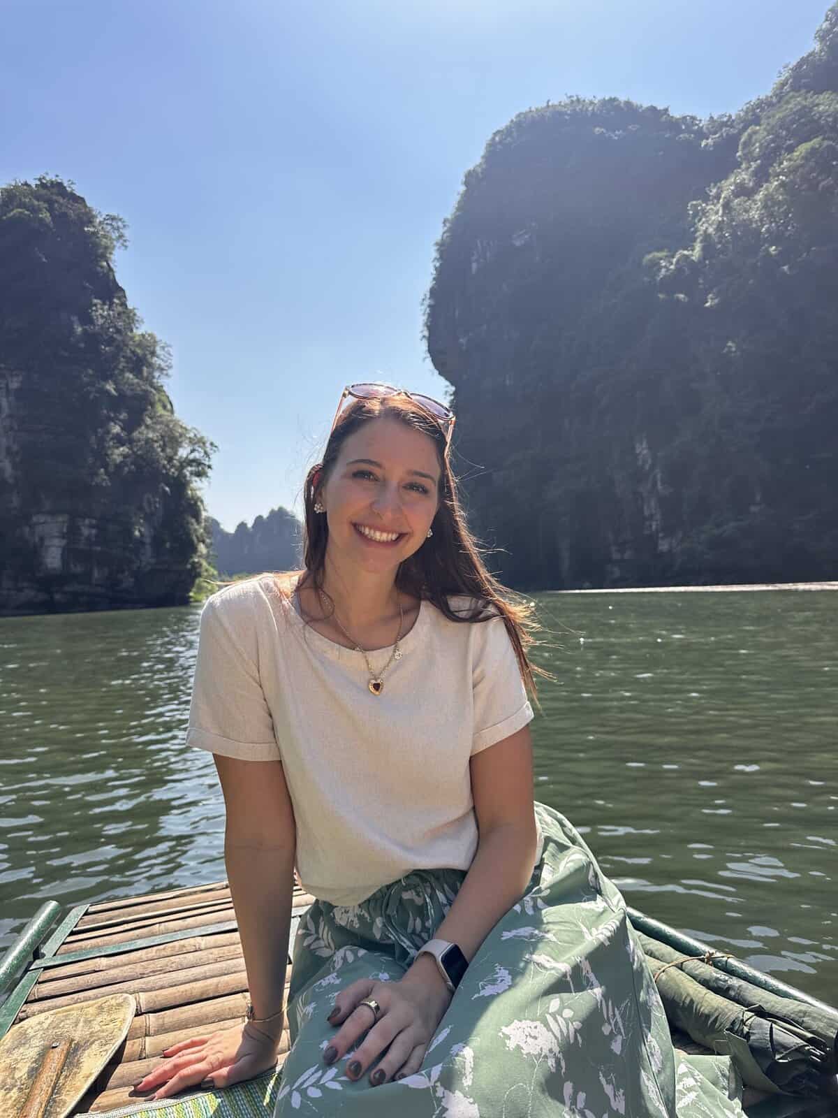 A girl sitting and smiling on a boat in Trang An.