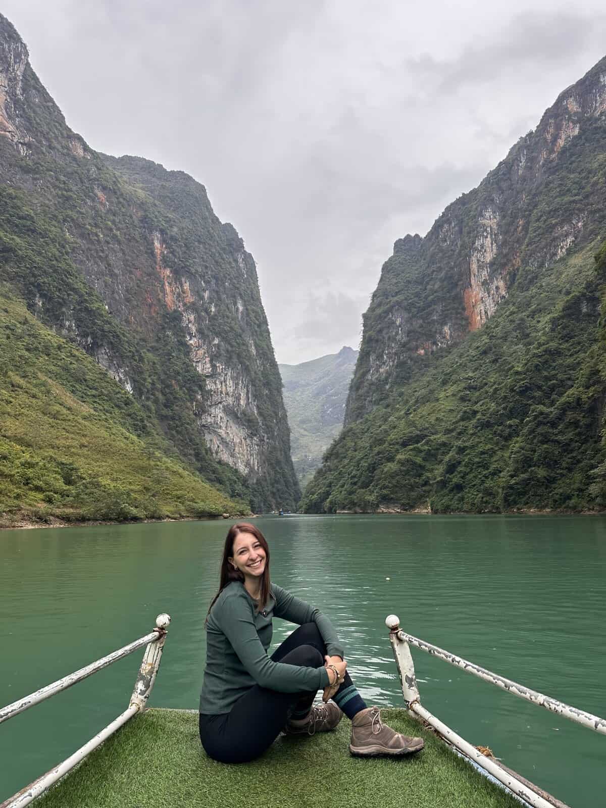 a girl on a boat smiling in front of a vietnamese canyon