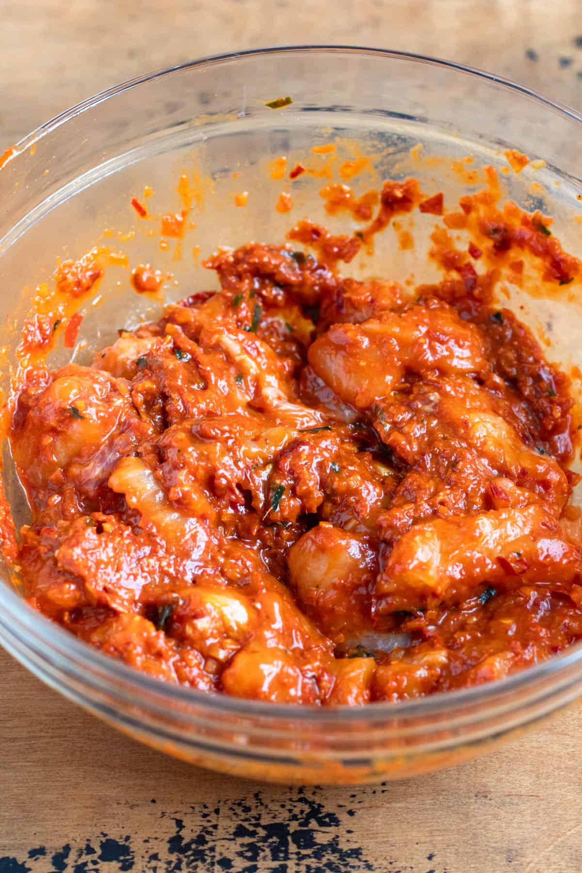 Raw catfish pieces mixed with egg and curry paste in a bowl, fully coated.