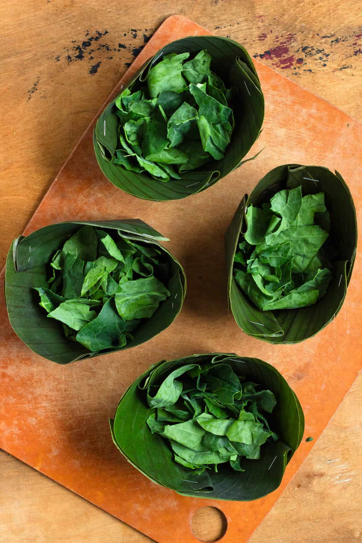 Banana leaf bowls lined with fresh Chinese broccoli leaves.