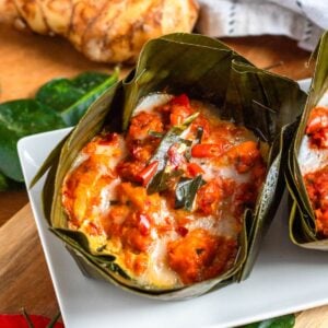 Cambodian Amok Curry topped with red chilies, served on a white plate.