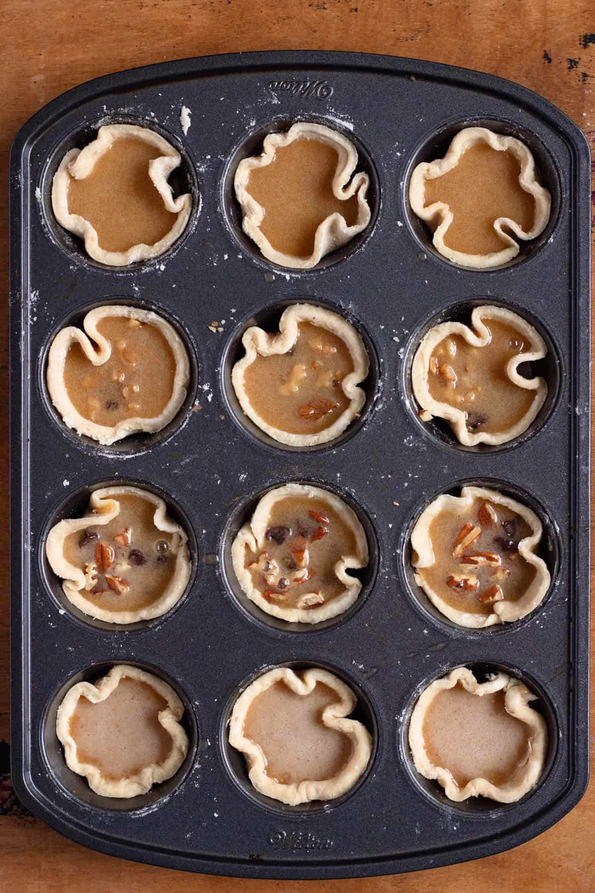 Add-ins being placed into pastry cups, then smooth liquid filling poured evenly into each shell.
