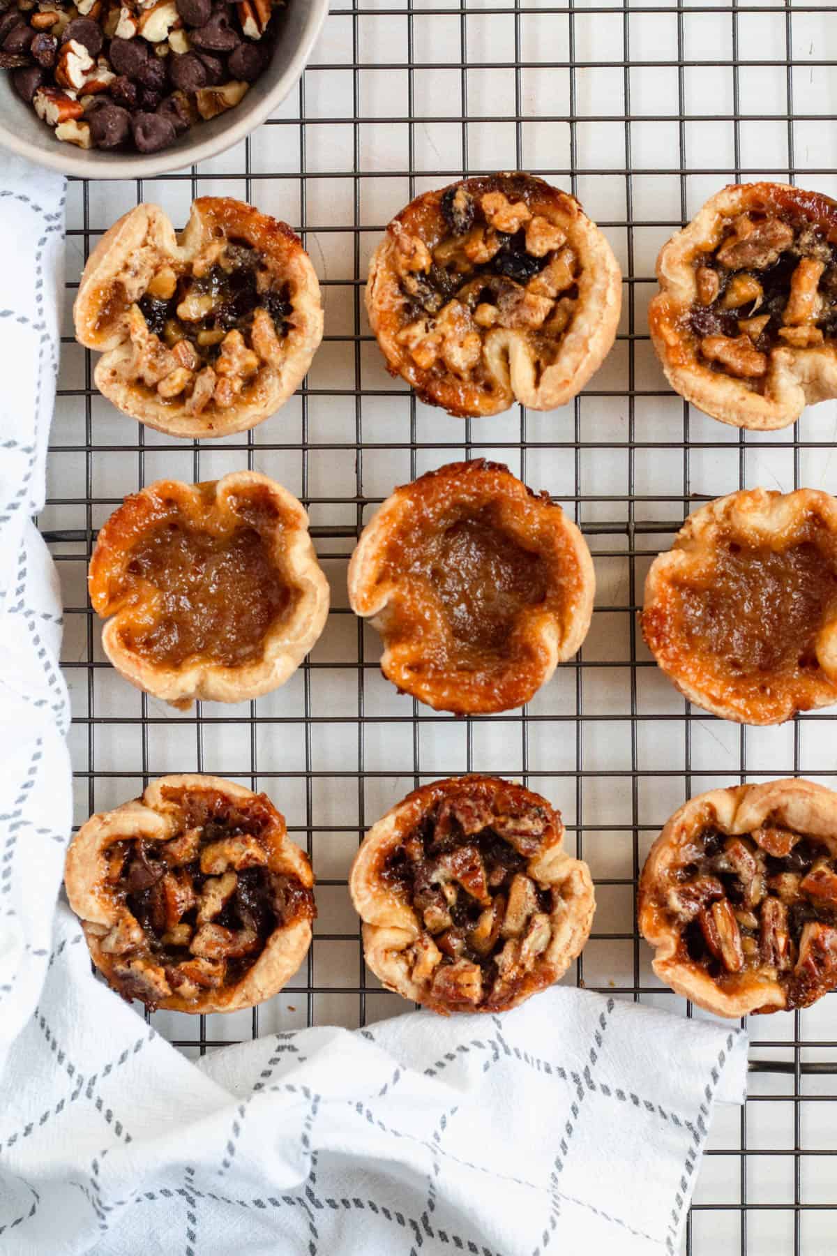 Assorted Authentic Canadian Butter Tarts with plain and nut fillings on a cooling rack.