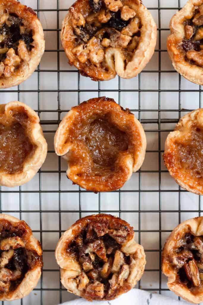 Assorted Authentic Canadian Butter Tarts with plain and nut fillings on a cooling rack.