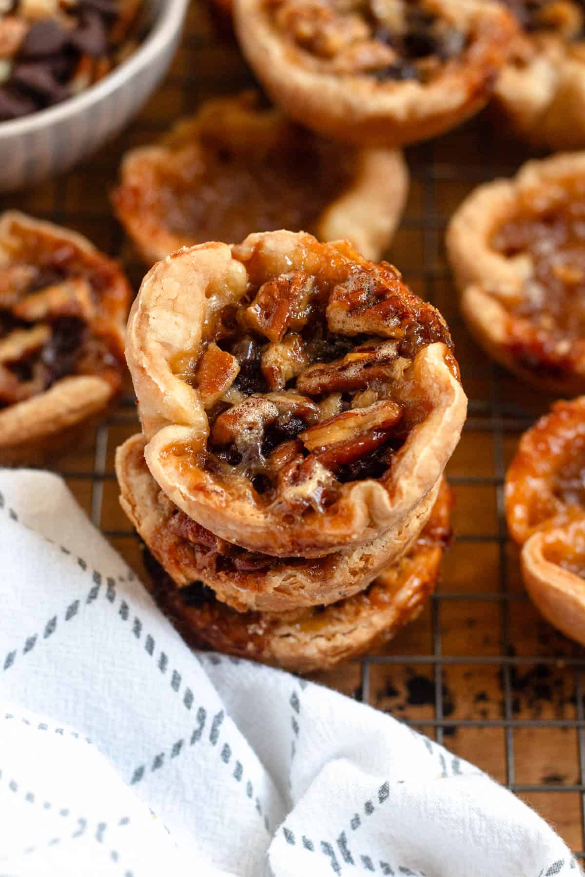 Stacked Authentic Canadian Butter Tarts filled with nuts and caramel on a cooling rack.