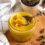A jar of golden Niter Kibbeh with a spoon scooping it.